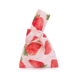 Detailed strawberry and floral print on soft velvet fabric of a pink knotted wrist bag