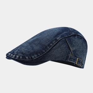 Detail of washed denim flat cap showing bronze metal buckle and reinforced stitching