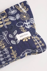 Detailed embroidery of floral patterns on navy linen makeup bag with brand label