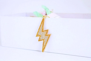 Macro shot of gold lightning bolt keychain pendant with yellow and clear crystals