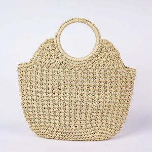 Handgefertigte beige Stroh-Handtasche mit rundem Griff für den Strandurlaub auf weiß