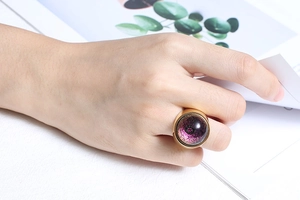 Detailed view of an oversized gold stainless steel ring with deep purple resin inlay