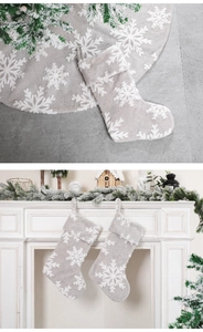 Détail du tapis de sapin gris pelucheux et des chaussettes assorties aux motifs de flocons