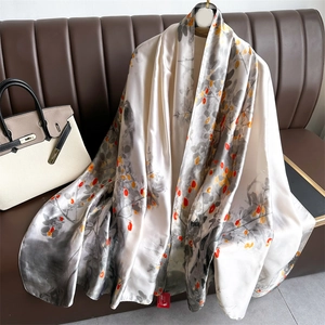 Elegant ink-wash floral silk scarf with bird pattern draped over a leather sofa