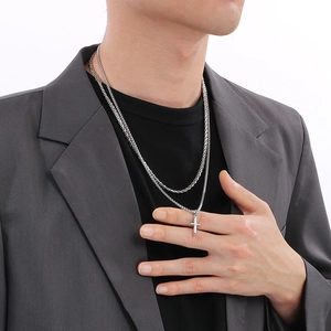 Men's silver layered stainless steel necklace with a cross pendant on a model
