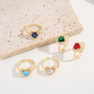 Close-up of heart-shaped zircon rings in five colors on a textured stone base