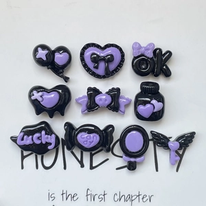 Detail showing 9 pieces of black and purple resin cabochons in bows and hearts shapes