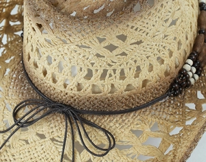 Detail of hollow woven straw hat with bohemian colorful beads and brown string bow