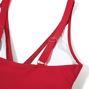 Detail of red high-waisted swimsuit showing adjustable straps and silver metal buckles