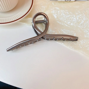 Close-up of a gunmetal irregular geometric hair claw clip on a minimalist white desk