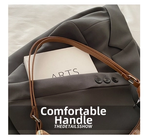 Close-up of brown leather handles and textured fabric on a large capacity tote bag