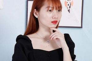 Close-up of heart-shaped necklace with red stone and matching white stud earrings