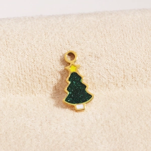 Detail eines 18K Gold Weihnachtsbaum-Anhängers mit grünem Glitzer auf weichem beigem Plüsch