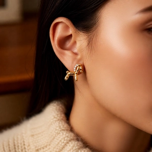 Detailed close-up of a model wearing a gold balloon dog earring with white zircon stones