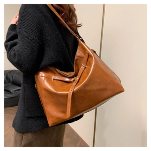 Detail view of large brown leather tote bag with vintage texture worn on shoulder