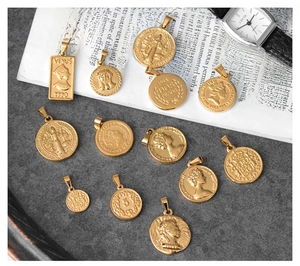 Flat lay of vintage 18K gold plated coin pendants with Roman and Queen Elizabeth motifs