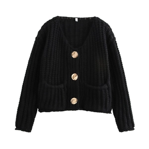 Detail of black knit cardigan featuring gold buttons, V-neckline and large front pockets