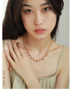 Close-up of 18k gold-plated bead necklace with colorful drip oil charms on a model