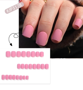 Detail of short square matte pink press-on nails showing applied look and full set layout