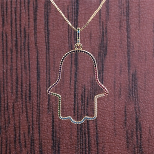Golden Hamsa hand pendant necklace with colorful gemstones on a brown wooden background