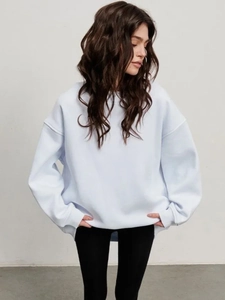 Detail of light blue oversized sweatshirt showing loose fit and ribbed cuffs on sleeves