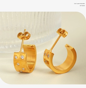 Macro shot of 18k gold-plated C-shaped earrings with inlaid sparkling zircon stones