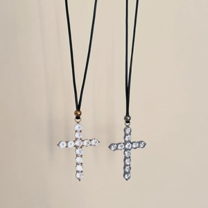 Detail of cross pendants with white zircon inlays on adjustable black wax cords