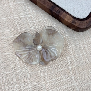 Detailed close-up of a flower-shaped acetate hair clip with a central pearl embellishment