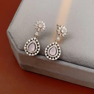 Detail view of silver drop earrings with pink zircons and small diamonds on grey velvet box