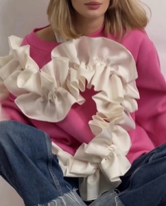 Détail du sweat rose avec décoration de cœur en satin blanc et volants élégants
