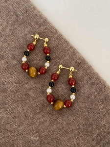 Detailed shot of bohemian beaded hoop earrings with agate and pearl on brown sweater