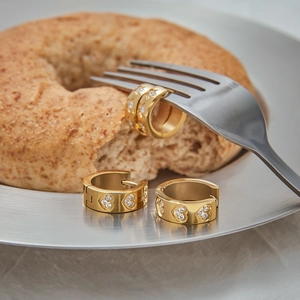 Gold stainless steel hoop earrings with sparkling zircon hearts on creative background