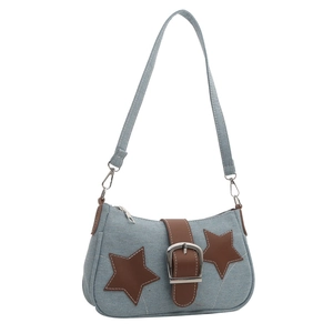 Detail of denim shoulder bag featuring star patches and brown leather buckle strap