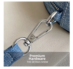 Macro detail of the silver metal lobster clasp and D-ring on blue denim crossbody bag