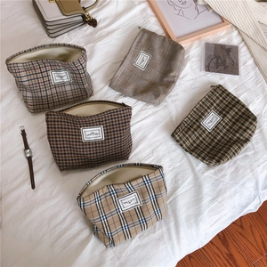 Flat lay of vintage plaid canvas cosmetic bags in various patterns on white fabric