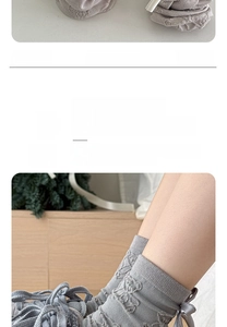 Detail of light gray knitted crew socks featuring a ribbon bow and textured ribbed fabric