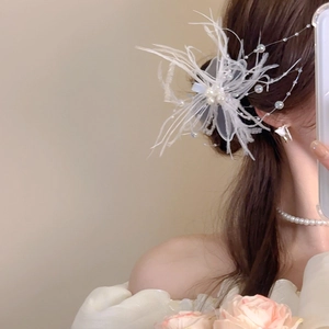 Détail d'une pince à cheveux en plumes blanches et perles portée dans un style romantique