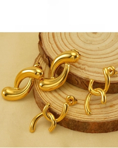 Macro detail of 18k gold plated irregular hoop earrings on a natural wood surface
