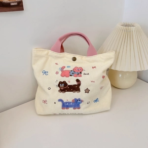 Détail du sac en velours côtelé crème avec broderies de chats de dessin animé et texte Luck