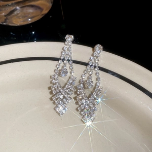 Detailed view of silver bow earrings with sparkling rhinestones and elegant tassels