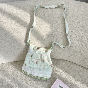 Détail du sac bandoulière à carreaux vert menthe avec motifs de lapins et dentelle