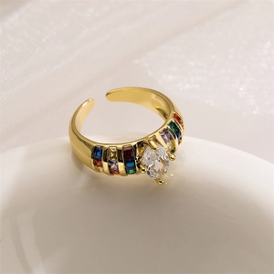 Detailed close-up of a gold-plated heart ring with rainbow zircons on white surface