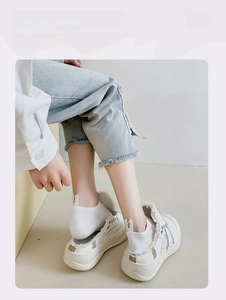 Detail of white low-cut socks with cartoon heel embroidery and frayed platform sneakers