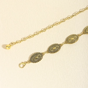 Detailed close-up of vintage gold metal waist chain with embossed sunburst pattern and clasp