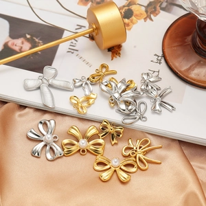 Golden and silver stainless steel bow pendants with pearls on elegant silk background