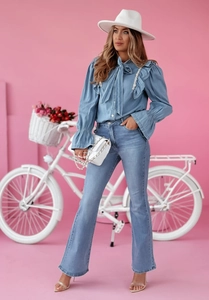 Ensemble chemise en jean et pantalon évasé avec chapeau blanc devant un mur rose