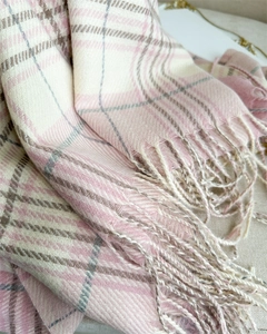 Detailed view of pink and beige plaid scarf texture with soft woven fringe edges