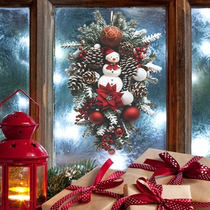 Christmas teardrop wreath with snowman, pine cones and red ornaments on frosted window