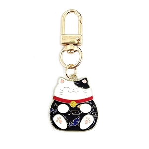 Close-up of Maneki-neko keychain featuring white enamel cat and golden lobster clasp