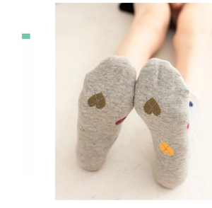 Detailed close-up of light grey cotton knit socks with colorful heart pattern print